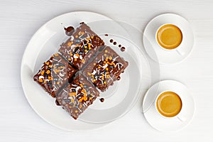 Homemade brownie and two cups of coffee espresso on white wooden table