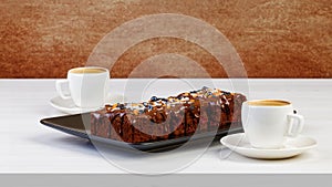 Homemade brownie and two cups of coffee espresso on white wooden table.