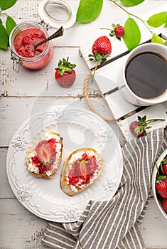 Homemade bruschetta with cottage cheese and strawberries for breakfast at white wooden background