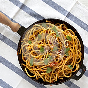 Homemade Bucatini all Amatriciana Pasta in a cast iron pan on cloth, overhead view. Flat lay, top view, from above