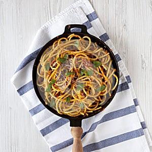 Homemade Bucatini all Amatriciana Pasta in a cast iron pan on cloth, top view. Flat lay, overhead