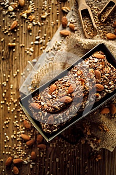 Homemade buckwheat bread with the addition of nuts and seeds in a baking tin on a wooden table, top view.