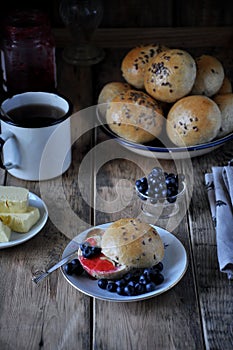 Homemade buns with linseed sunflower seeds for breakfast with butter and blueberry jam