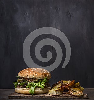 Homemade burger with tuna and fried potatoes with dill and garlic on a cutting board wooden rustic background border, place for