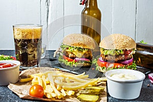 Homemade burgers with beef and fried potatoes and glass of cold dark beer on stone table