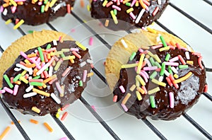 homemade butter cookies dipped in chocolate and sugar sprinkle dots on wire rack.