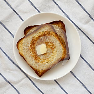 Homemade Buttered Toast on a white plate, top view. Flat lay, overhead, from above