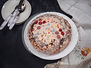 Homemade cake with caramel dressing on a white plate in the background saucer and cutlery. Next to the cake plate there is a