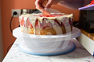 Homemade Cake with Hand Placing Strawberry on Top