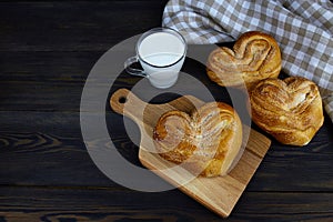 Homemade cakes and a cup of milk on a wooden board on a dark background