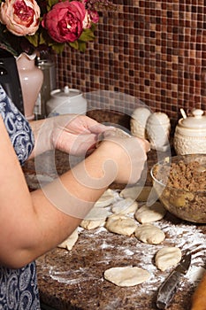 Homemade cakes of the dough in the women`s hands. The process of making pies with meat and potatoes dough by hand