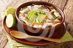 Homemade Caldo tlalpeno is a Mexican chicken soup topped with avocado and cheese close-up in a bowl. horizontal