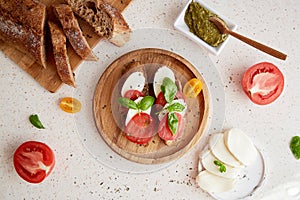 Homemade caprese sandwich Italian starter, snack with fresh mozzarella, tomatoes, basil leaves and pesto sauce with