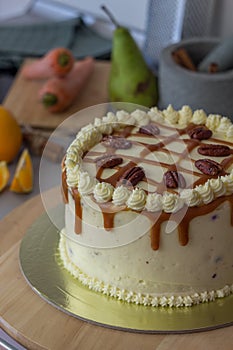 Homemade carrot cake with cream cheese frosting, caramel sauce and pecan nuts topping