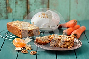 Homemade carrot cake with fresh carrots and clementines on turquoise background