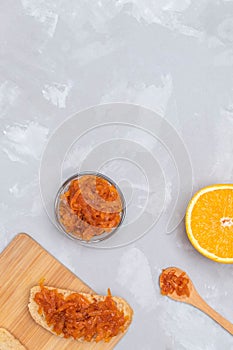 Homemade carrot jam with toasts on concrete background