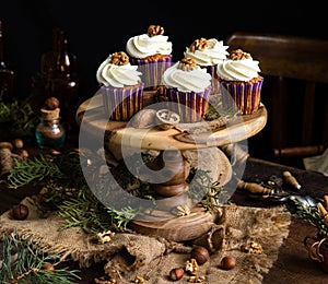 Homemade carrot or pumpkin cupcakes with white cream and walnut on top