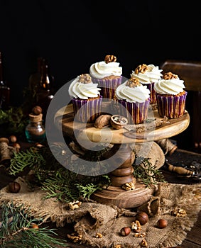 Homemade carrot or pumpkin cupcakes with white cream and walnut on top