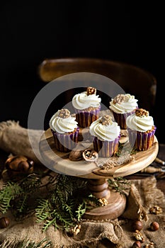 Homemade carrot or pumpkin cupcakes with white cream and walnut on top