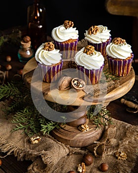 Homemade carrot or pumpkin cupcakes with white cream and walnut on top