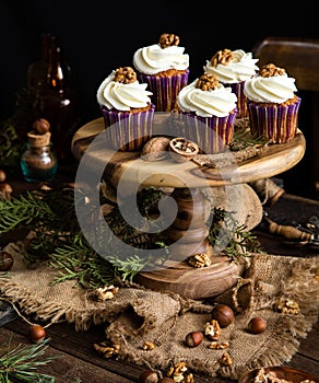 Homemade carrot or pumpkin cupcakes with white cream and walnut on top