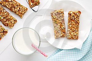 Homemade cereal snacks for healthy eating. Granola bars with milk on white wooden background.
