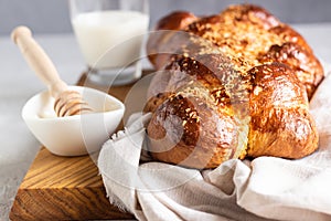 Homemade challah bread on a wooden cutting board over light grey stone background.