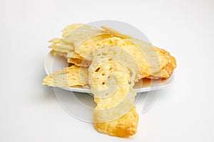 Homemade cheese cracker on a white plate on uniform background with soft light ans shadows. Handmade food is simple and is made of