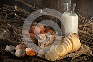 homemade cheese on craft paper next to milk and chicken eggs.