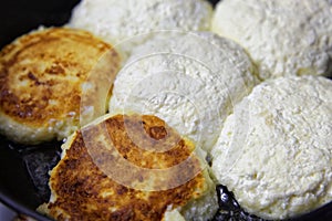 Homemade cheese pancakes or syrniki are fried in a frying pan. Traditional rustic food in Russian and Belarusian cuisines.