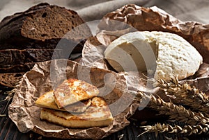 homemade cheese on a wooden board next to bread