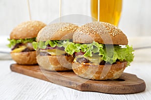 Homemade cheeseburgers on rustic wooden board and glass of cold beer, side view. Closeup. Selective focus