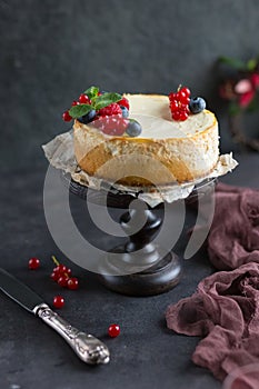 Homemade cheesecake with fresh berries on a dark wooden stand. New York cheesecake. Homemade cake.