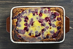 Homemade cherry pie in a ceramic form on a wooden table, closeup, top view