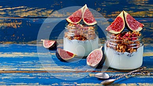 Homemade chia milk pudding with granola and fresh figs in the glass jars on the blue kitchen table. Detox superfoods breakfast