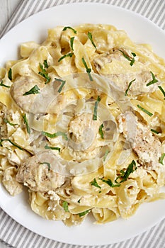 Homemade Chicken Fettuccine Alfredo in a plate on a white wooden table, top view. Flat lay, overhead, from above. Close-up