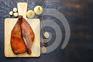 Homemade chicken legs fried on a barbecue and spices on a cutting board on a black background. Top view from above. Copy space