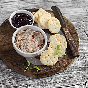 Homemade chicken liver pate, cranberry sauce and homemade cheese biscuits. Delicious snack or appetizer with wine. On light wooden