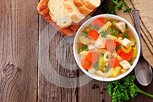 Homemade chicken noodle soup with vegetables, top view table scene on wood with copy space