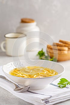 Homemade chicken noodle soup in a white plate, white background.