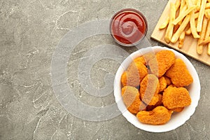 Homemade chicken nuggets and french fries with ketchup on grey background