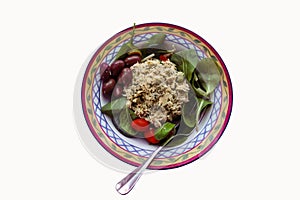 Homemade chicken salad served in a pretty bowl with spinach kalamata olives and cherry tomatoes - isolated on white