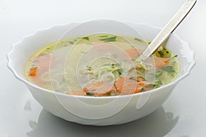 Homemade chicken soup with noodles and vegetables in a white bowl, white background. Healthy warm comfortable food