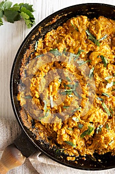 Homemade Chicken Tikka Masala in a cast iron pan on a white wooden background, top view. Flat lay, overhead, from above. Close-up