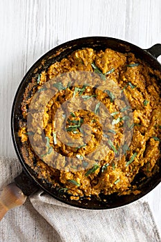 Homemade Chicken Tikka Masala in a cast iron pan on a white wooden surface, top view. Flat lay, overhead, from above. Close-up