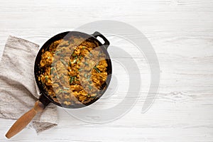 Homemade Chicken Tikka Masala in a cast iron pan on a white wooden table, top view. Flat lay, overhead, from above. Space for text