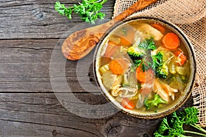 Homemade chicken vegetable soup, above view on rustic wood