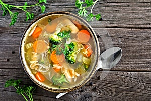 Homemade chicken vegetable soup, top view on rustic wood