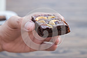 Homemade chocolate brownie with cashew nut in left hand