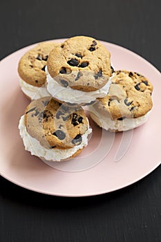 Homemade Chocolate Chip Cookie Ice Cream Sandwich on a pink plate on a black background, low angle view. Close-up